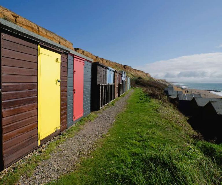 Colourful beach huts along the coastline of Barton-on-Sea, overlooking the sea.