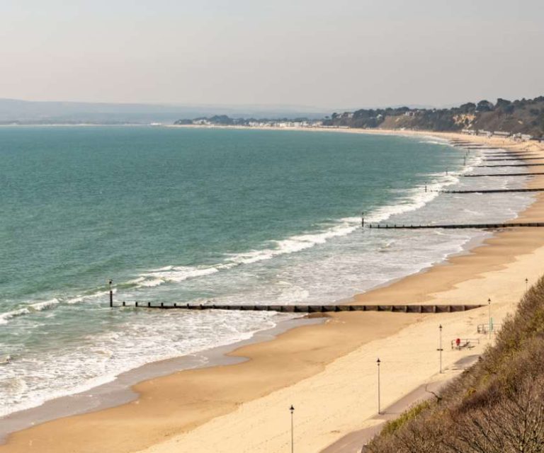 Expansive view of Bournemouth beach with calm waves meeting the sandy shore.