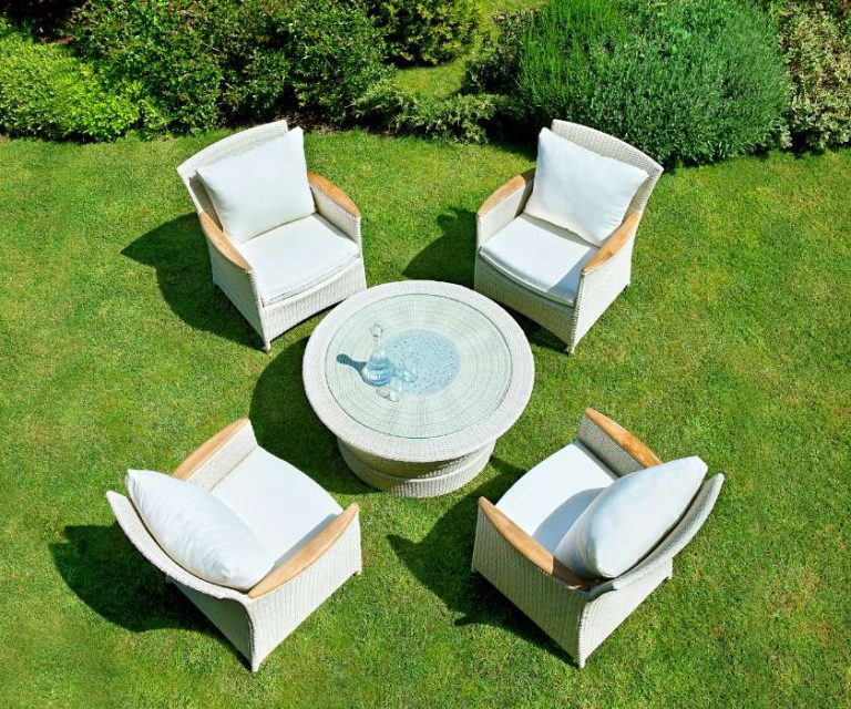 Outdoor seating area with white cushioned chairs and a glass-topped table, set on a lush green lawn in Hordle.