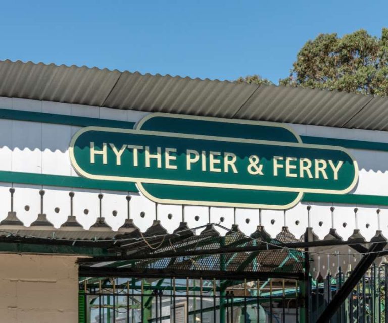 Green and white sign for Hythe Pier & Ferry, a local landmark.