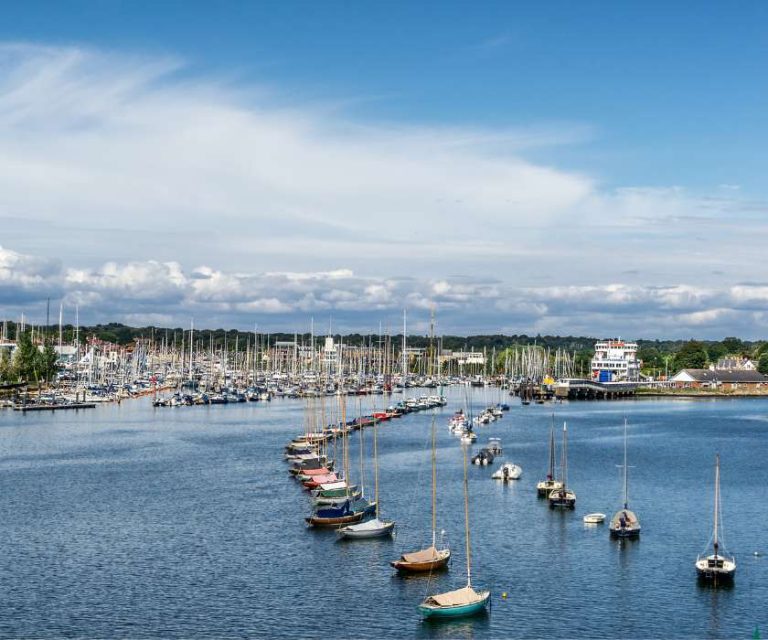 Scenic view of Lymington Harbour with boats moored in the calm water on a sunny day.