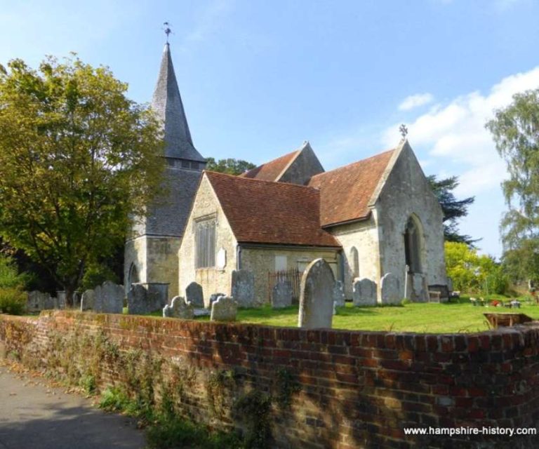 Charming old church surrounded by a low brick wall and gravestones in Nursling.