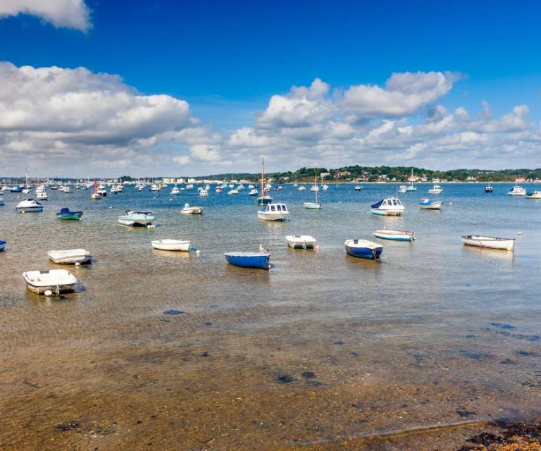 Numerous small boats floating in the tranquil waters of Poole Harbour.