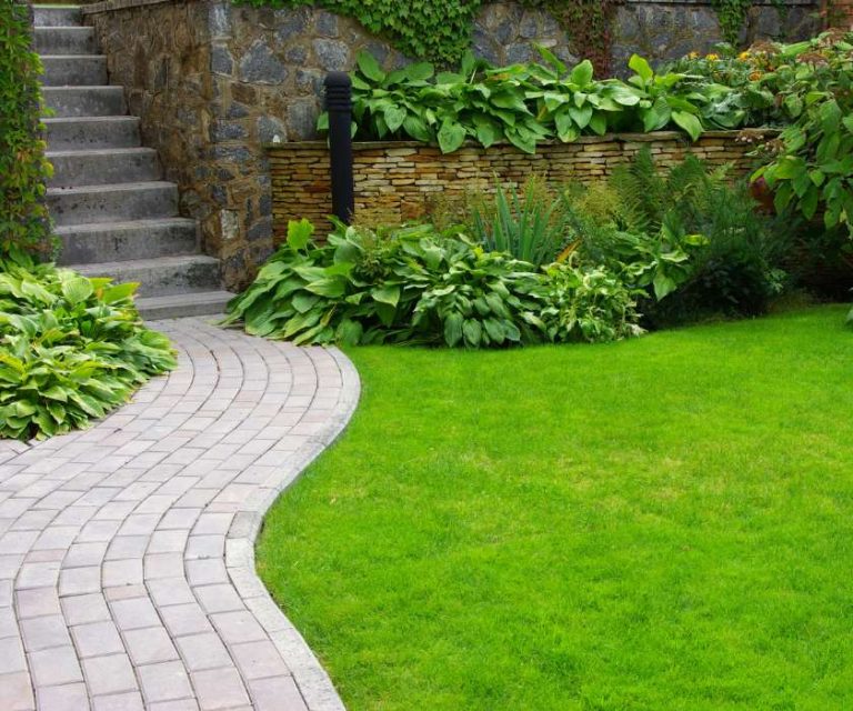 Curved stone pathway leading through a landscaped garden with greenery and a stone retaining wall in Verwood